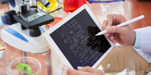 Scientist drawing chemical formulas and making calculations on tablet computer