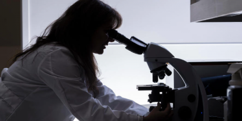 female scientist looking though a microscope